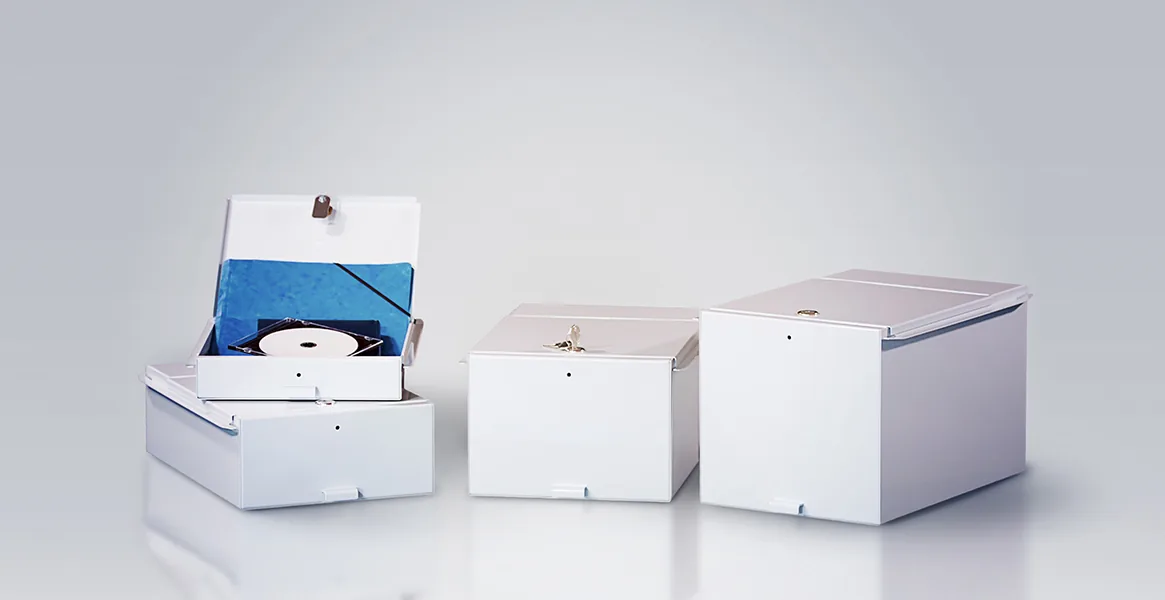 Drei verschiedene Schließfachboxen in unterschiedlichen Größen vor einem neutralen Hintergrund.