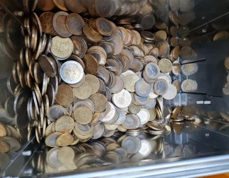 Ein Haufen verschiedener Euro-Münzen, darunter 1- und 2-Euro-Münzen sowie mehrere Cent-Münzen, füllt einen Behälter.